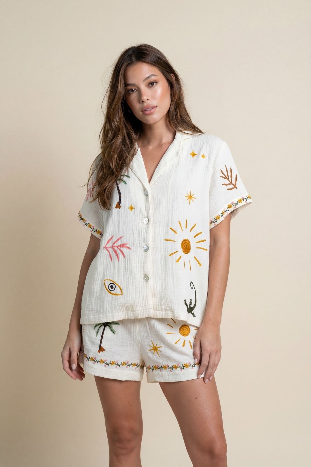 Woman wearing a white outfit with colorful embroidery on a beige background