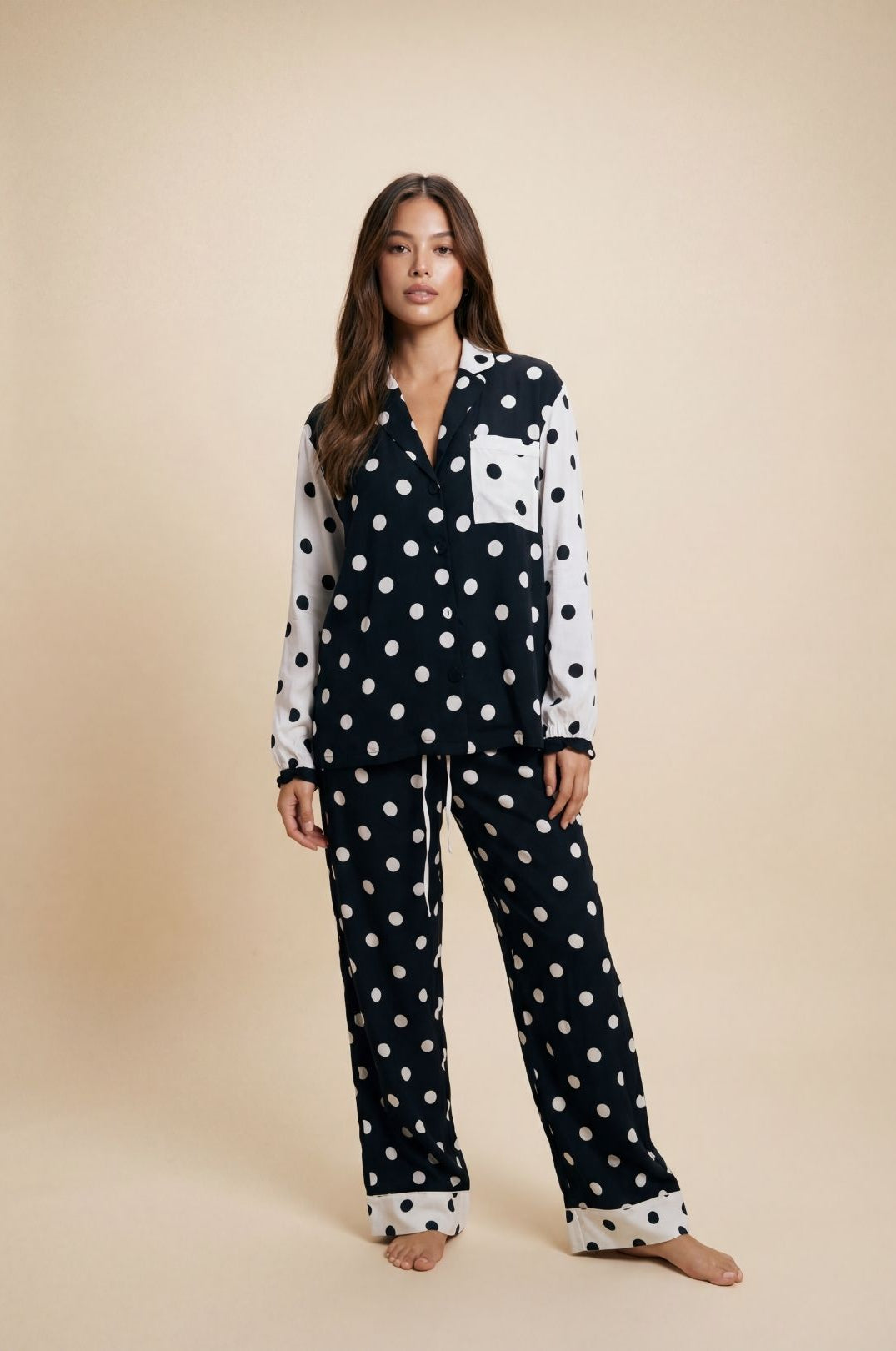 Woman wearing a black and white polka dot pajama set on a beige background
