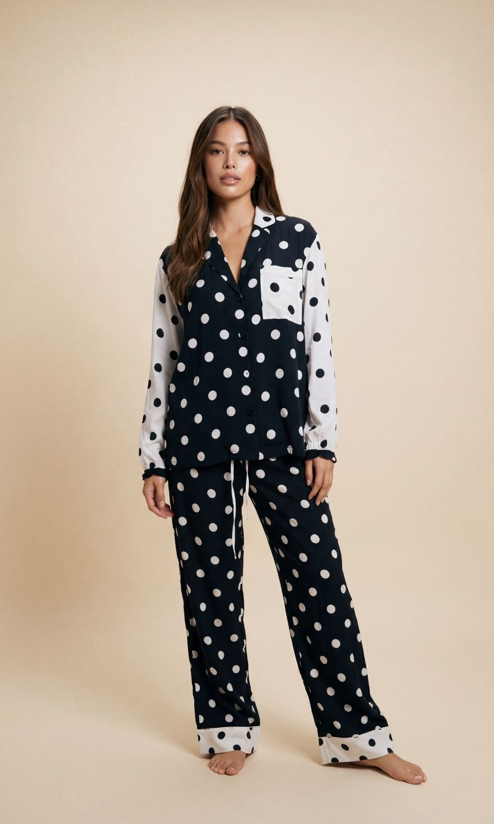 Woman wearing a black and white polka dot pajama set on a beige background