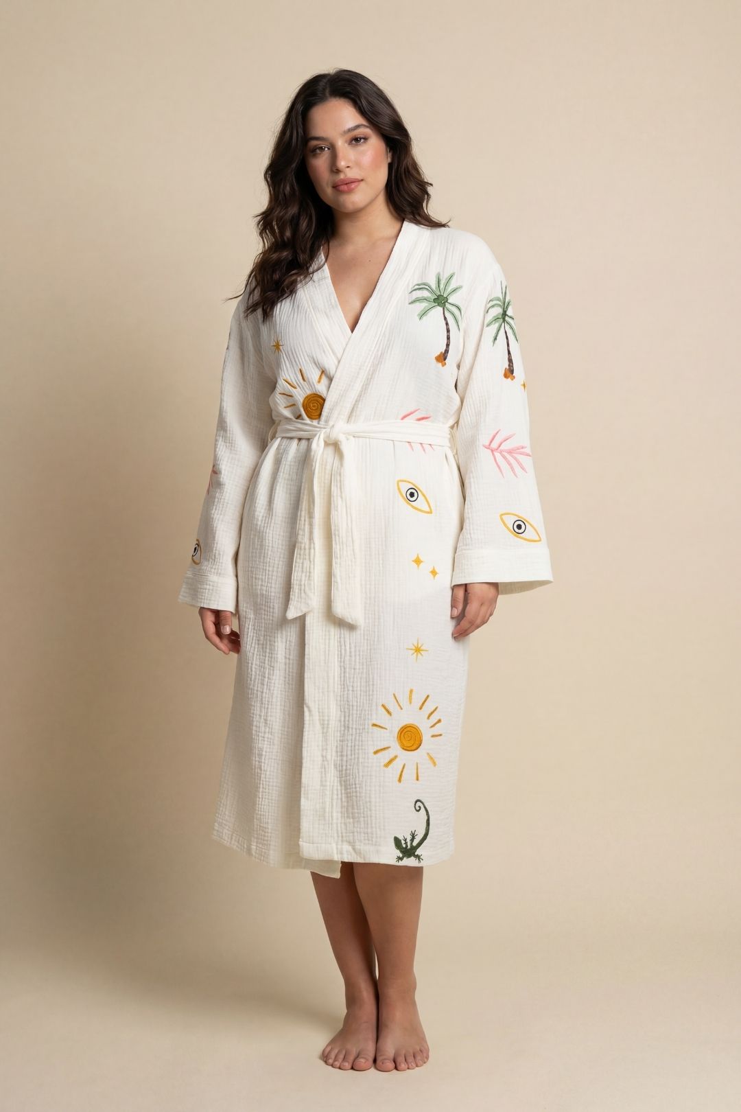 Woman wearing a white robe with floral and sun designs on a beige background