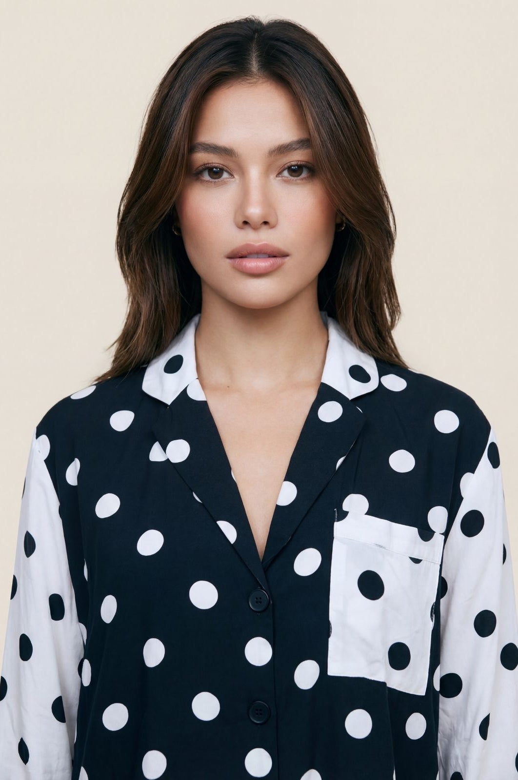 Woman wearing a black and white polka dot shirt against a beige background
