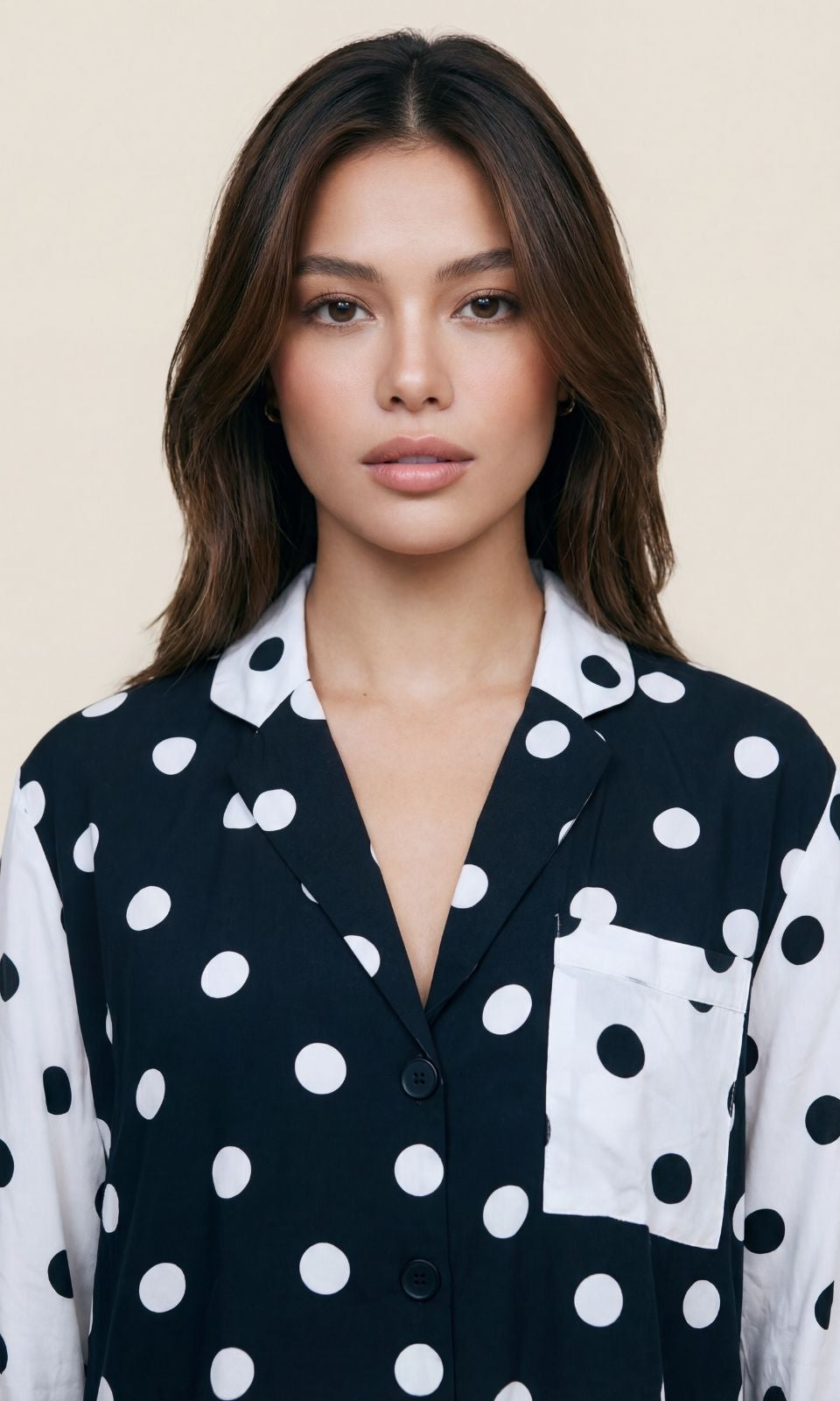 Woman wearing a black and white polka dot shirt against a beige background