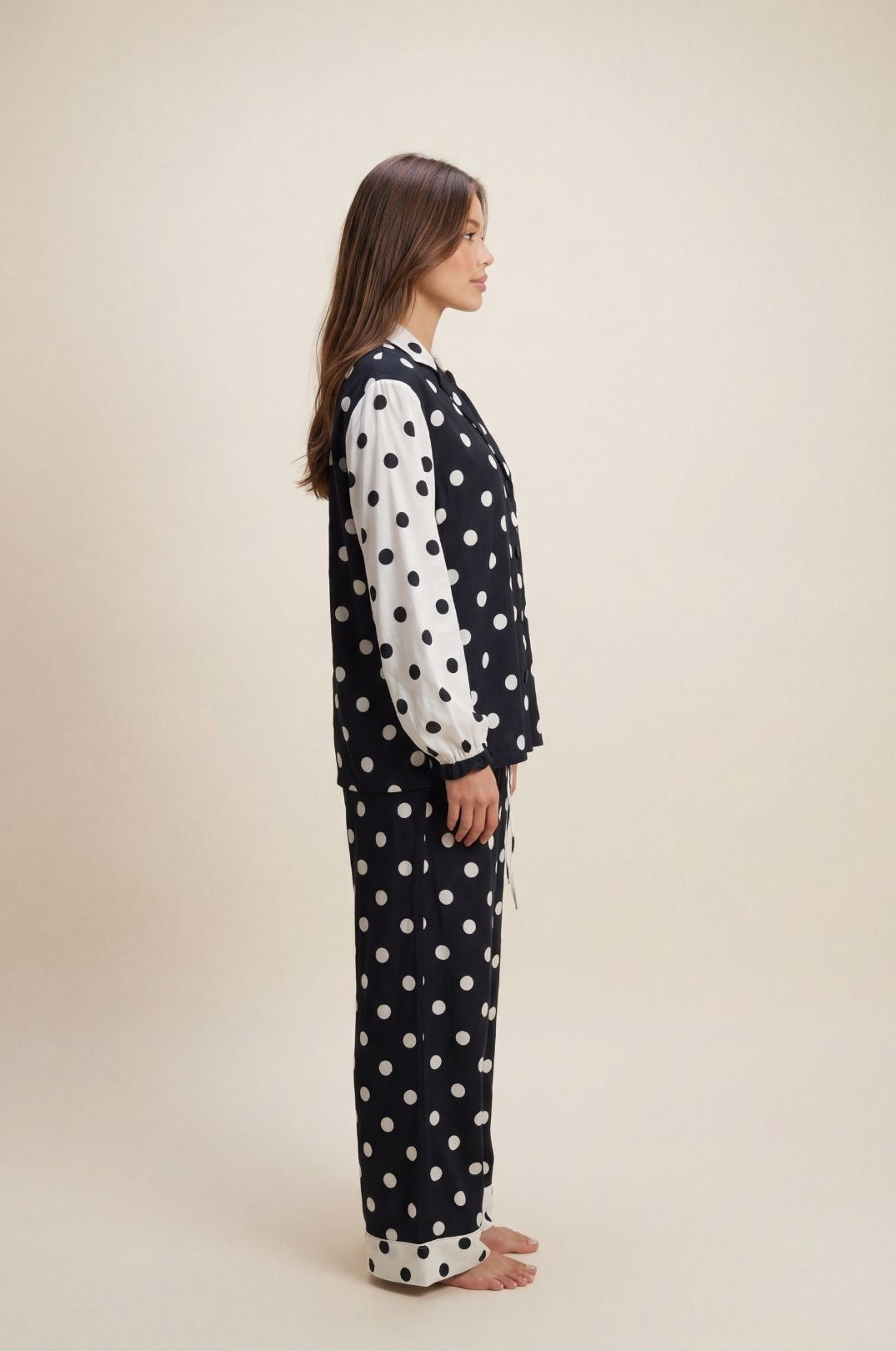 Woman wearing a polka dot pajama set on a beige background