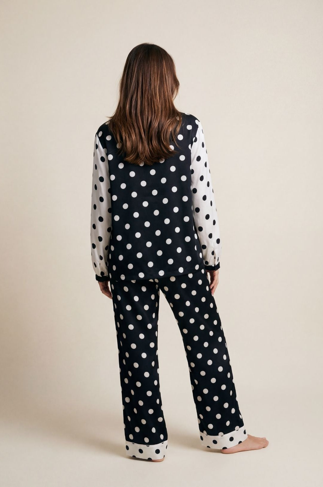 Person wearing a black polka dot outfit on a beige background