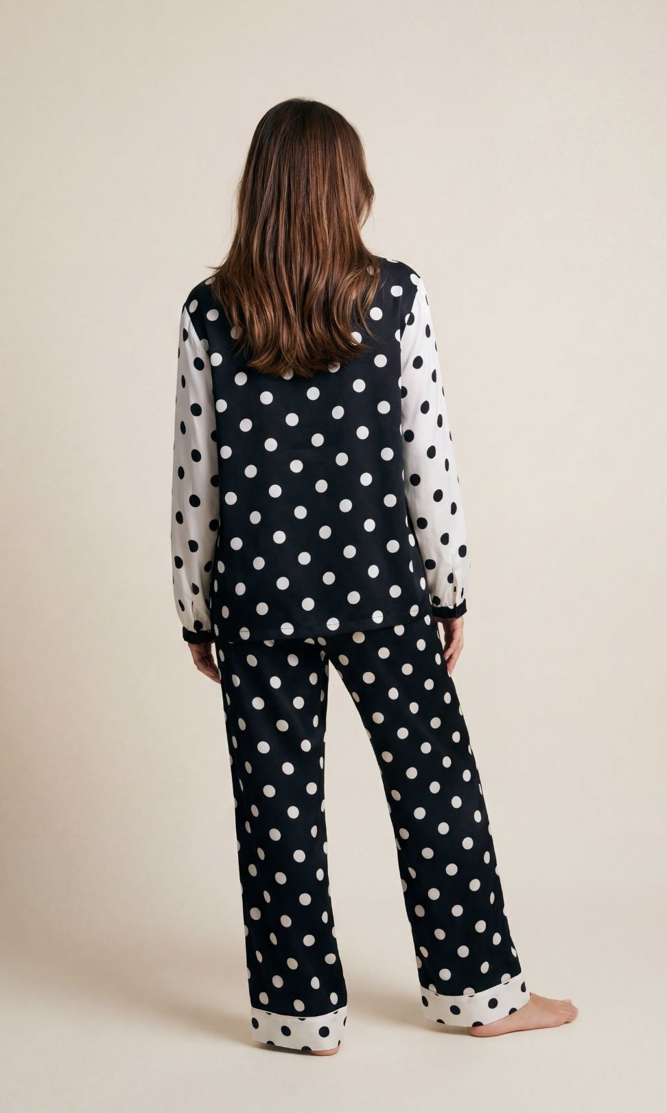 Person wearing a black polka dot outfit on a beige background