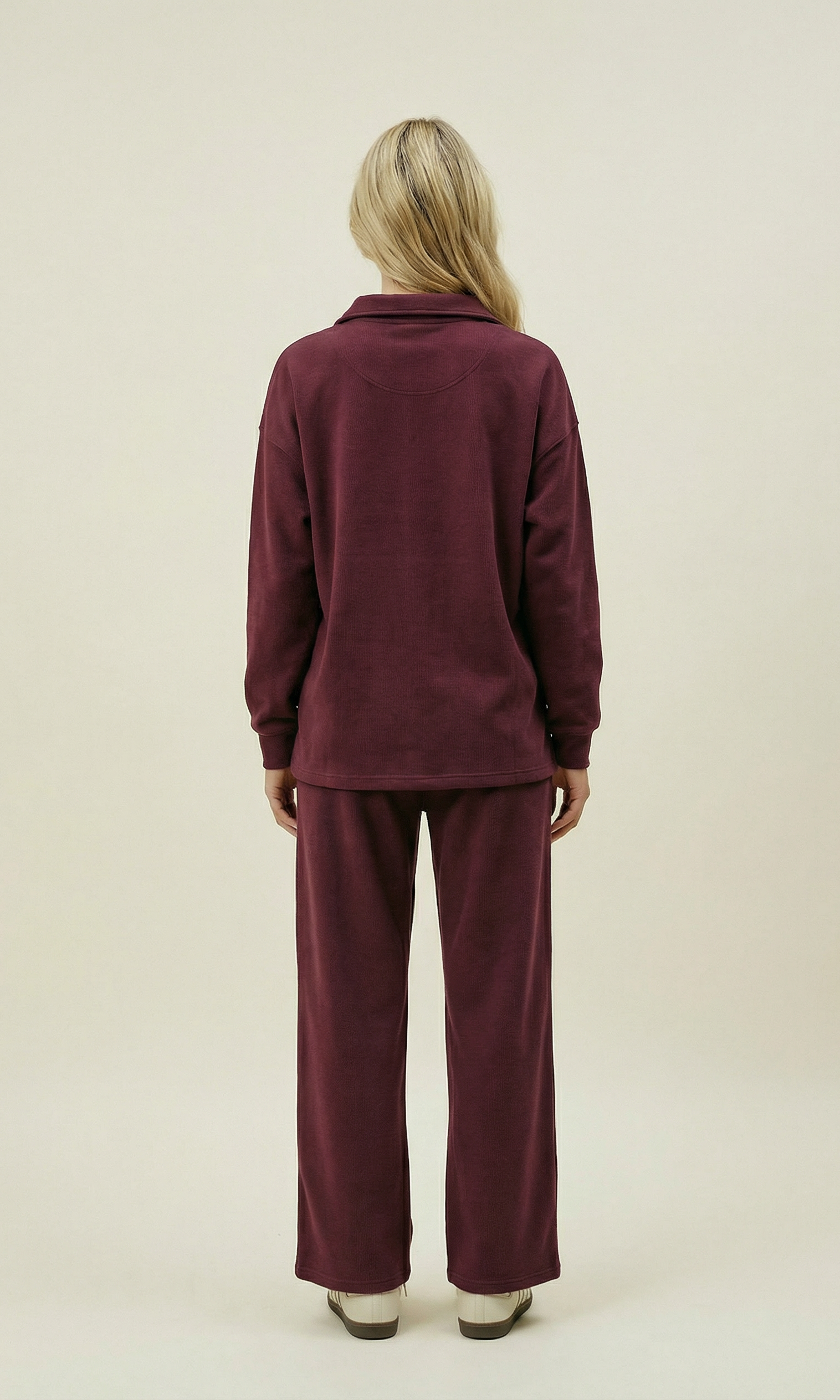 Person wearing a burgundy tracksuit on a beige background