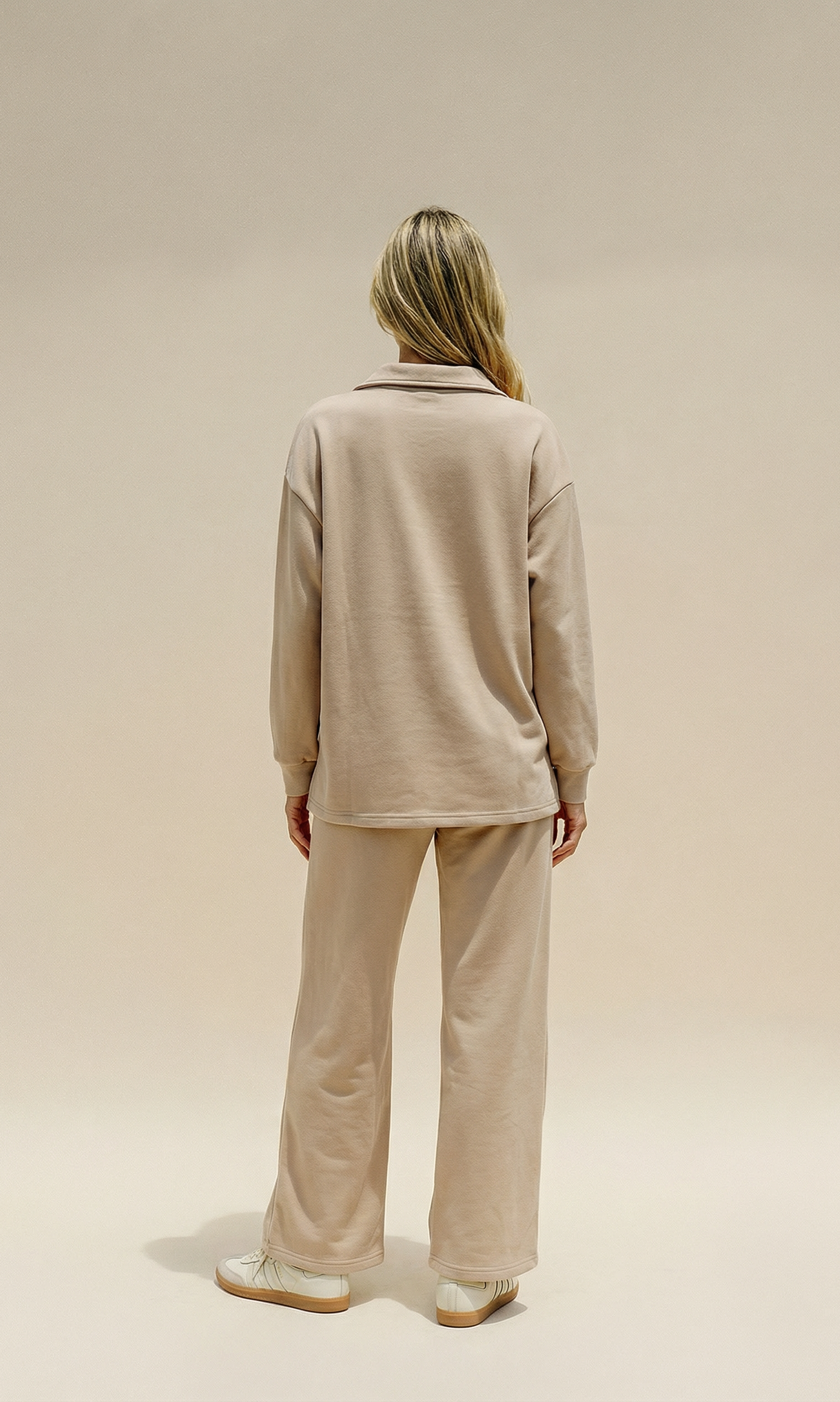 Person wearing a beige outfit on a plain background