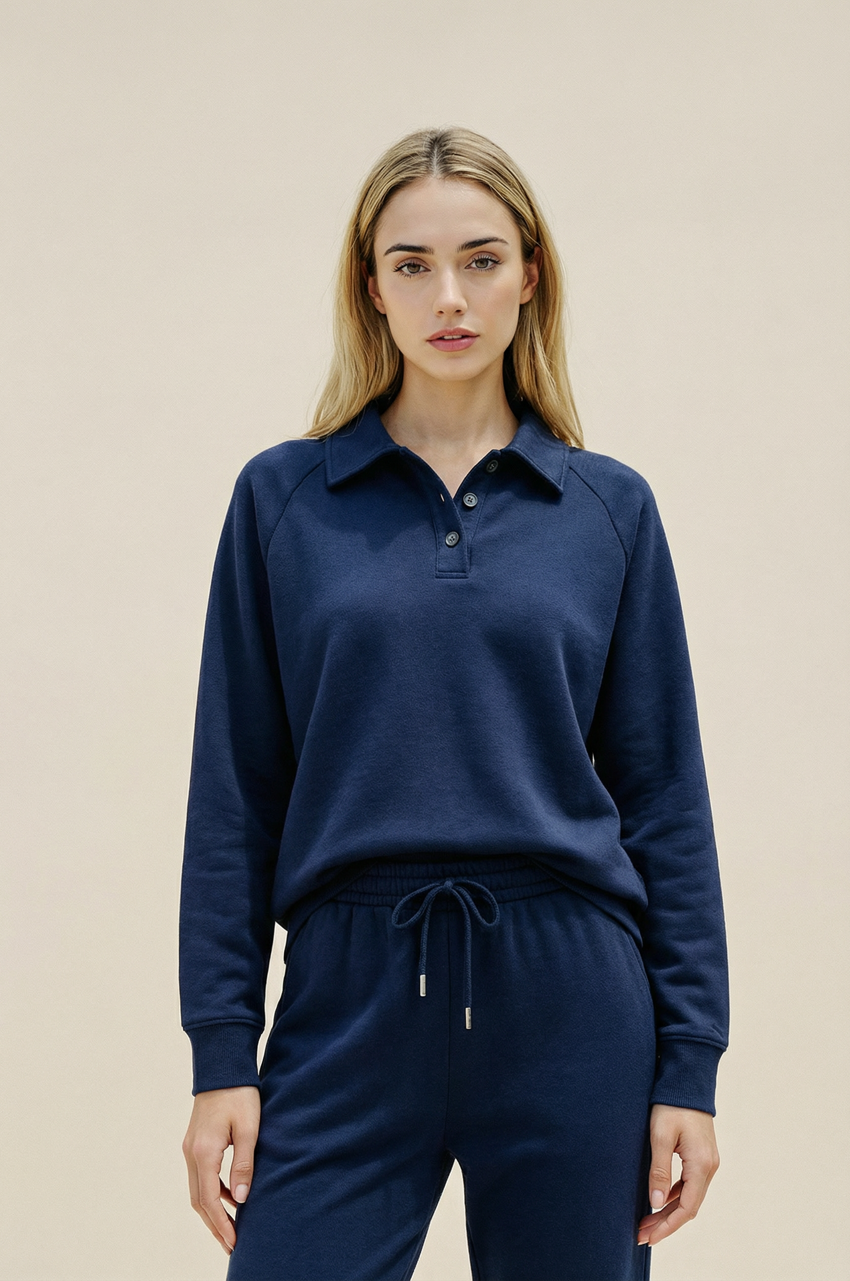 Woman wearing a navy blue long-sleeve shirt and matching pants against a beige background