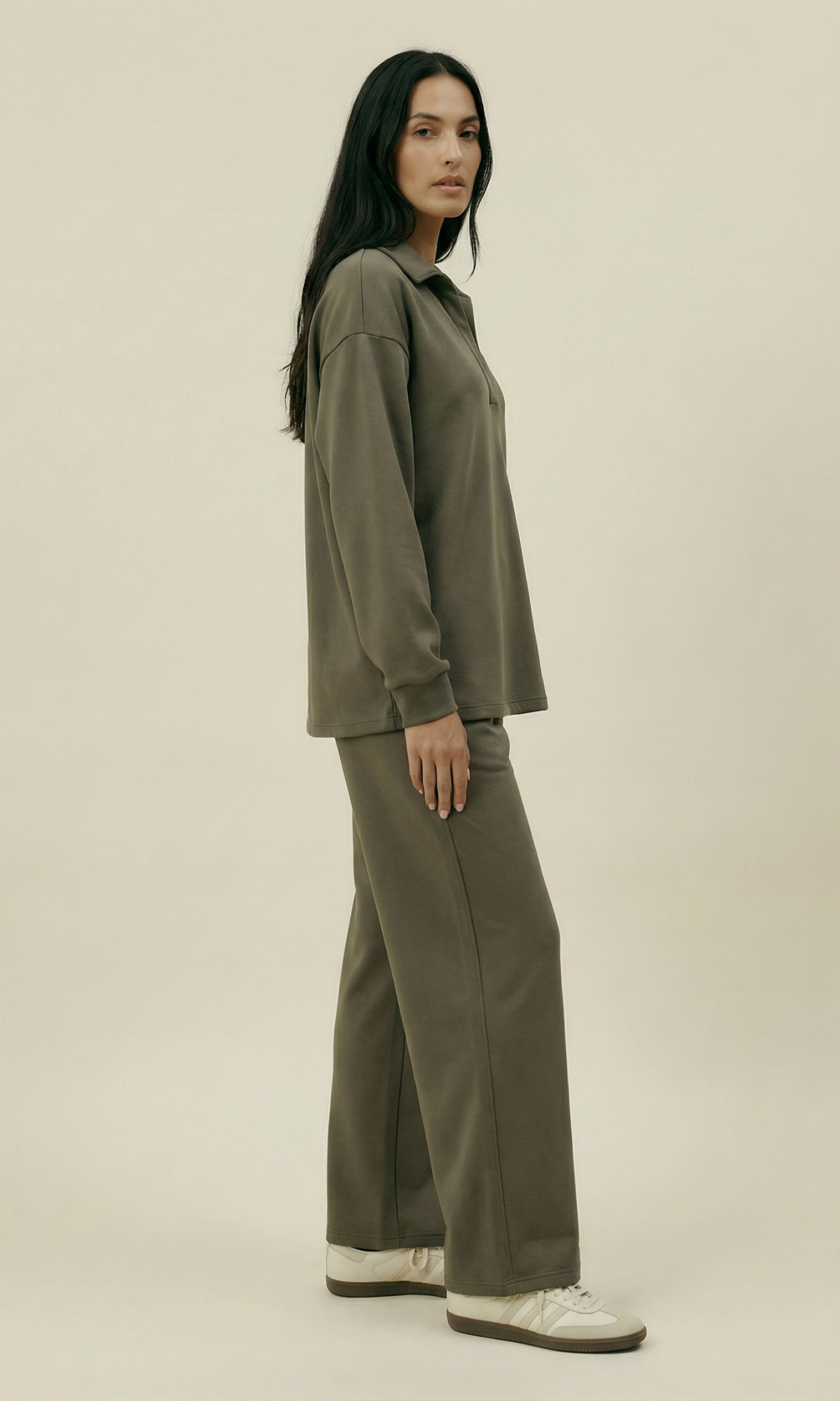 Woman wearing an olive green outfit on a beige background