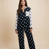 Woman wearing a black and white polka dot pajama set on a beige background