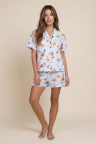 Woman wearing a light blue pajama set with orange and white pattern on a beige background