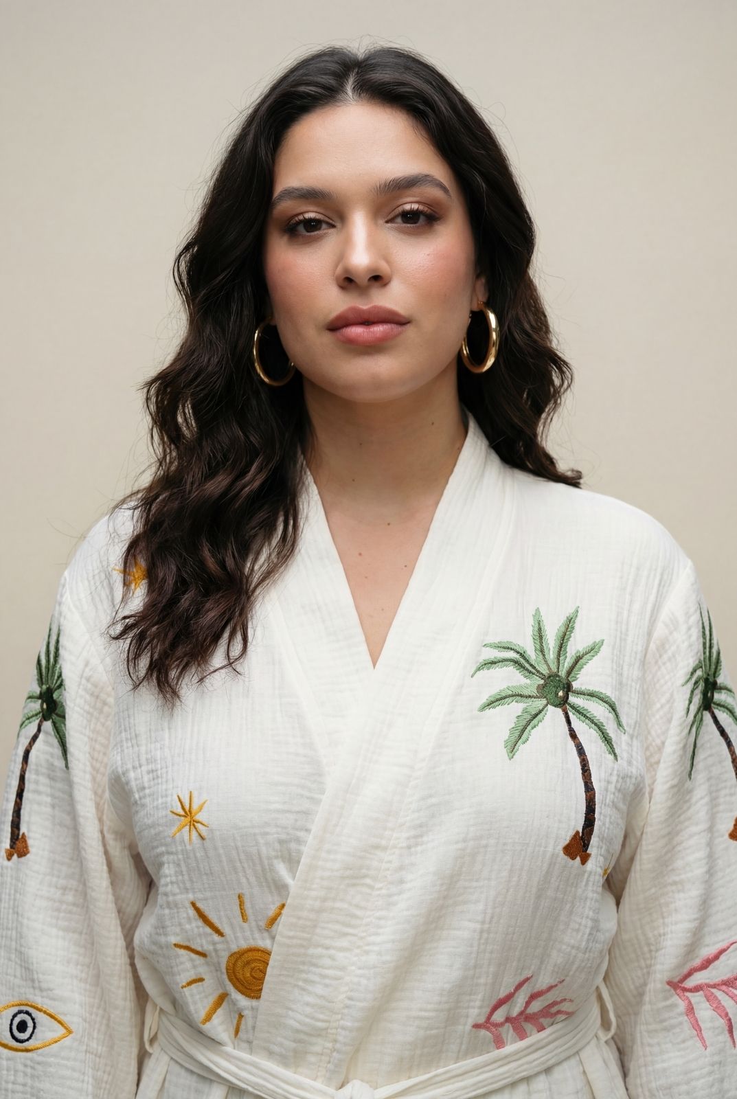 Woman wearing a white outfit with palm tree and sun designs against a beige background