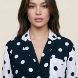 Woman wearing a black and white polka dot shirt against a beige background