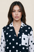 Woman wearing a black and white polka dot shirt against a beige background
