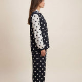 Woman wearing a polka dot pajama set on a beige background