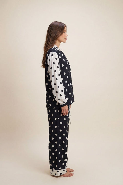 Woman wearing a polka dot pajama set on a beige background