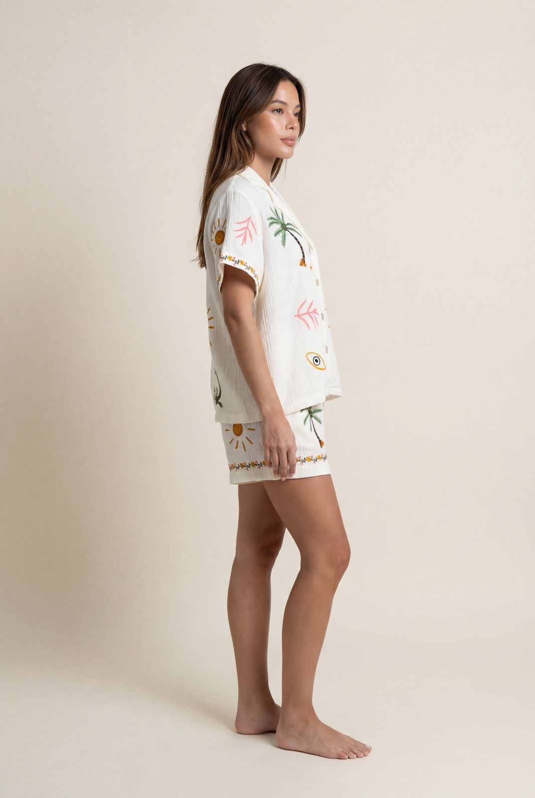 Woman wearing a white outfit with tropical patterns on a beige background