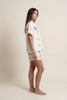 Woman wearing a white outfit with tropical patterns on a beige background