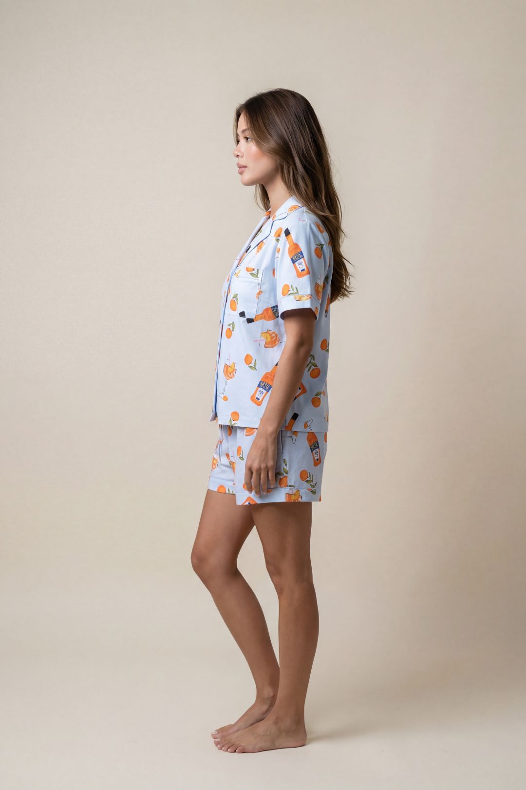 Woman wearing a light blue pajama set with orange patterns on a beige background