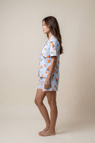 Woman wearing a light blue pajama set with orange patterns on a beige background