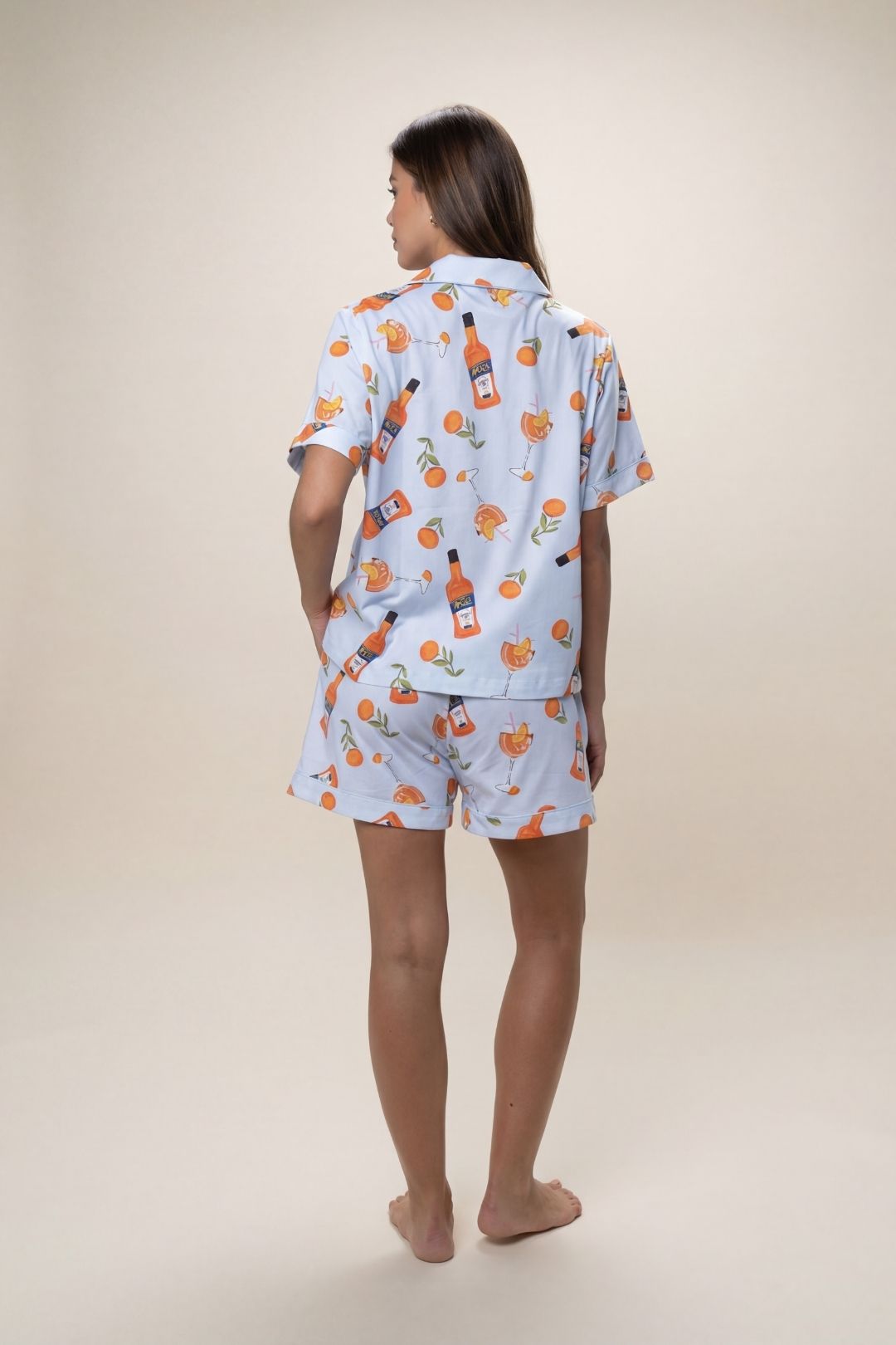Person wearing a matching pajama set with a bottle and orange pattern on a light blue background.