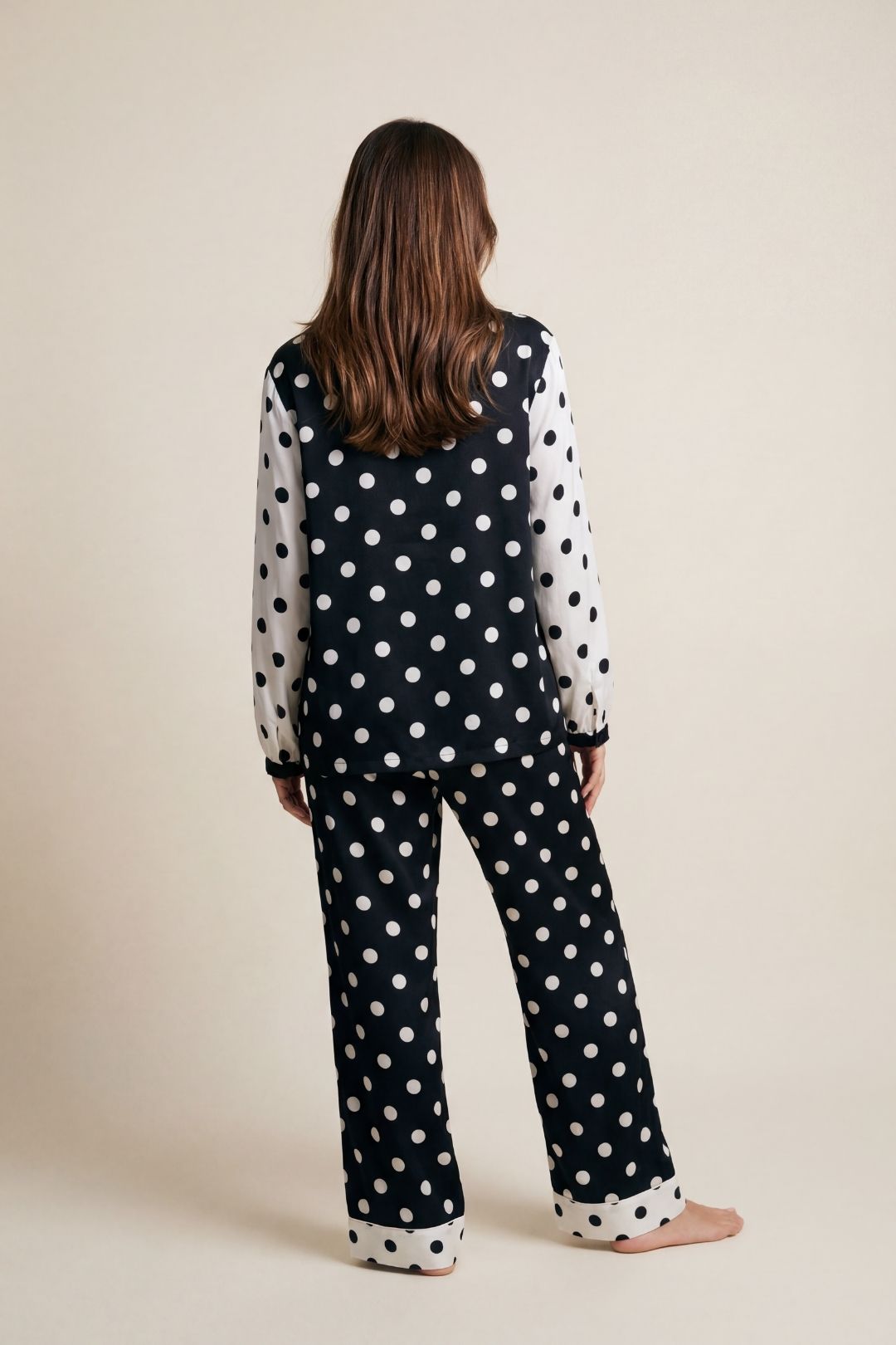 Person wearing a black polka dot outfit on a beige background