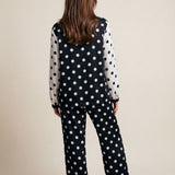 Person wearing a black polka dot outfit on a beige background