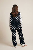 Person wearing a black polka dot outfit on a beige background