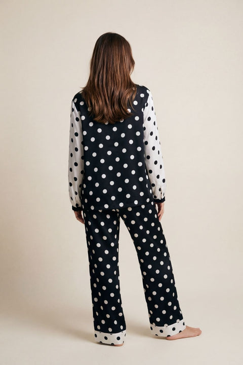 Person wearing a black polka dot outfit on a beige background