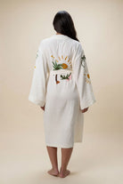 Person wearing a white embroidered robe on a beige background