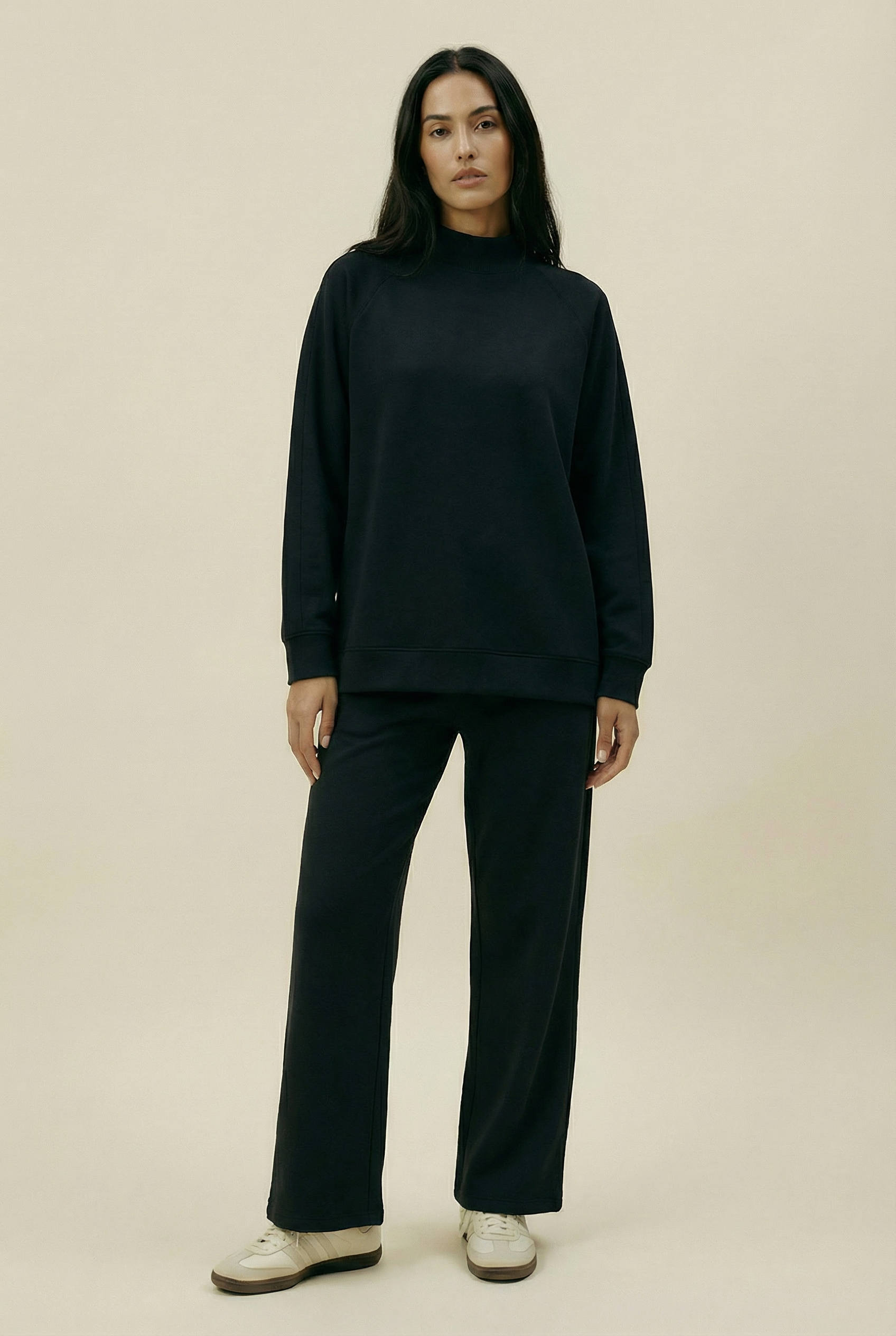 Person wearing a black outfit on a beige background