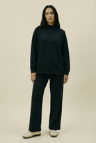 Person wearing a black outfit on a beige background