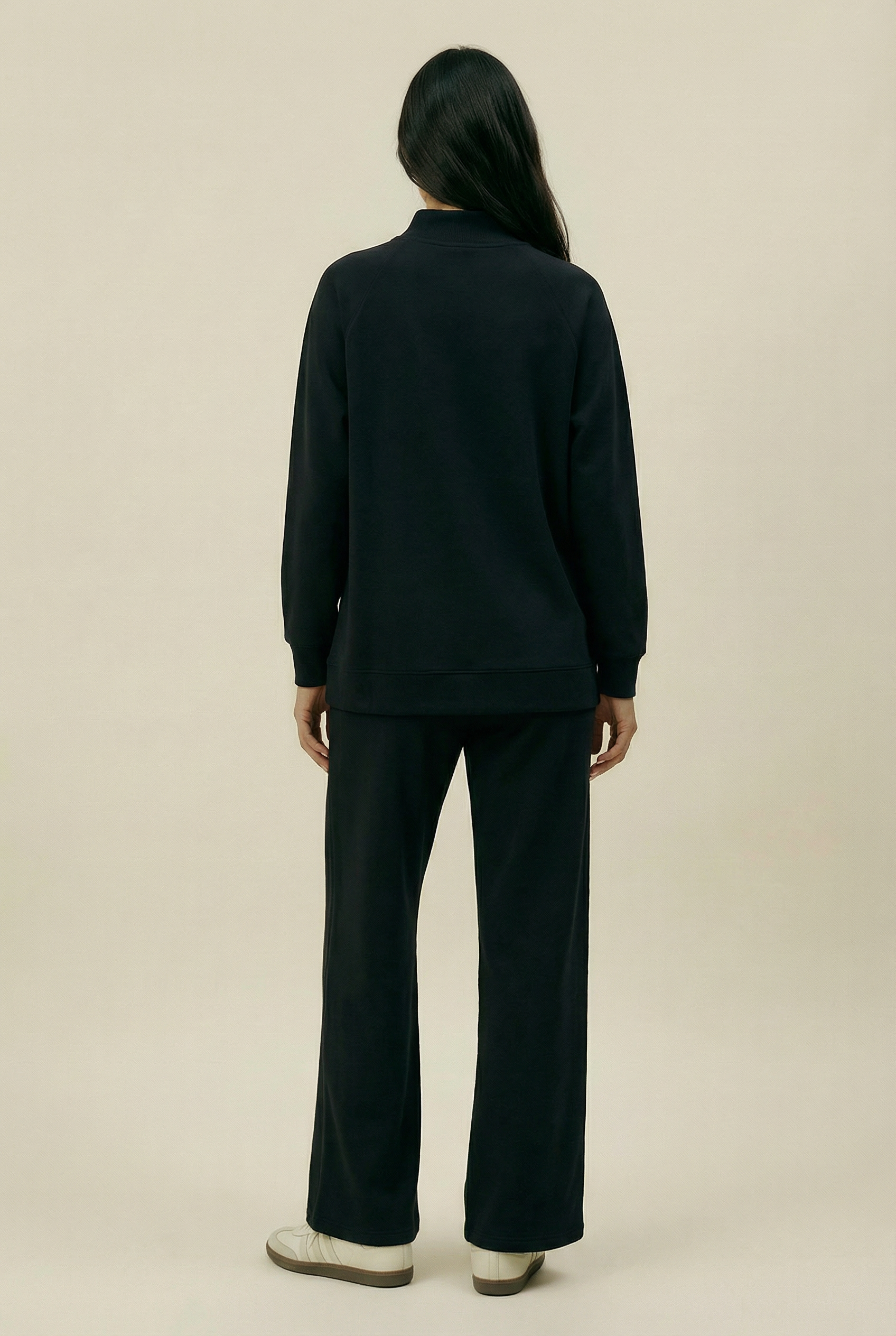 Person wearing a black outfit on a beige background