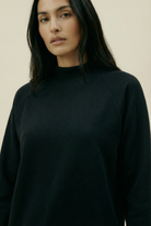 Woman wearing a black sweater against a beige background