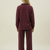 Person wearing a burgundy tracksuit on a beige background