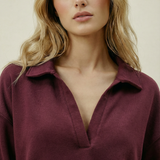Woman wearing a burgundy shirt against a plain background