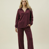 Woman wearing a burgundy outfit on a beige background