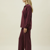 Woman wearing a burgundy outfit on a beige background