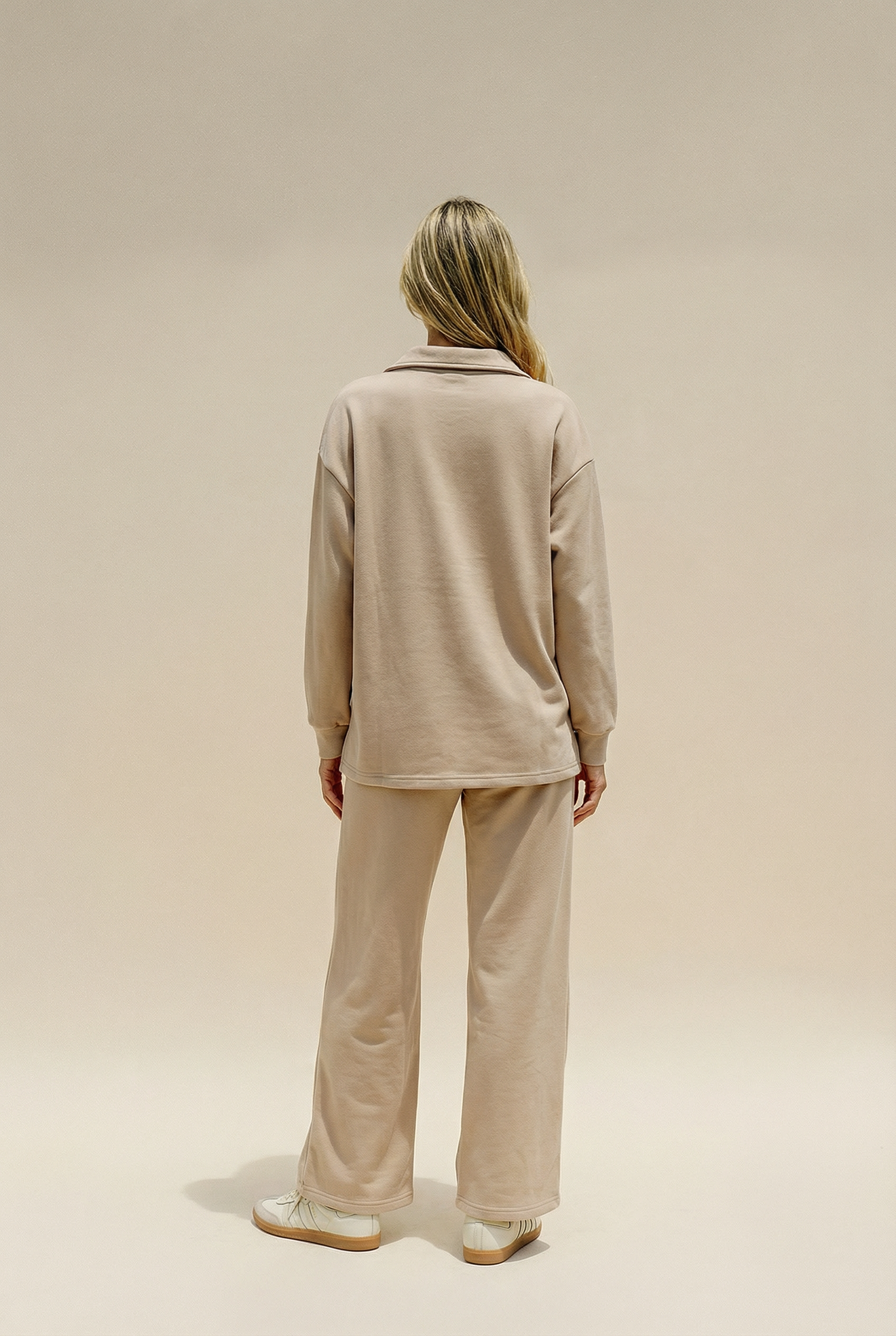 Person wearing a beige outfit on a plain background