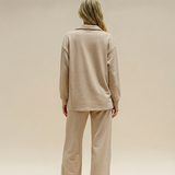 Person wearing a beige outfit on a plain background