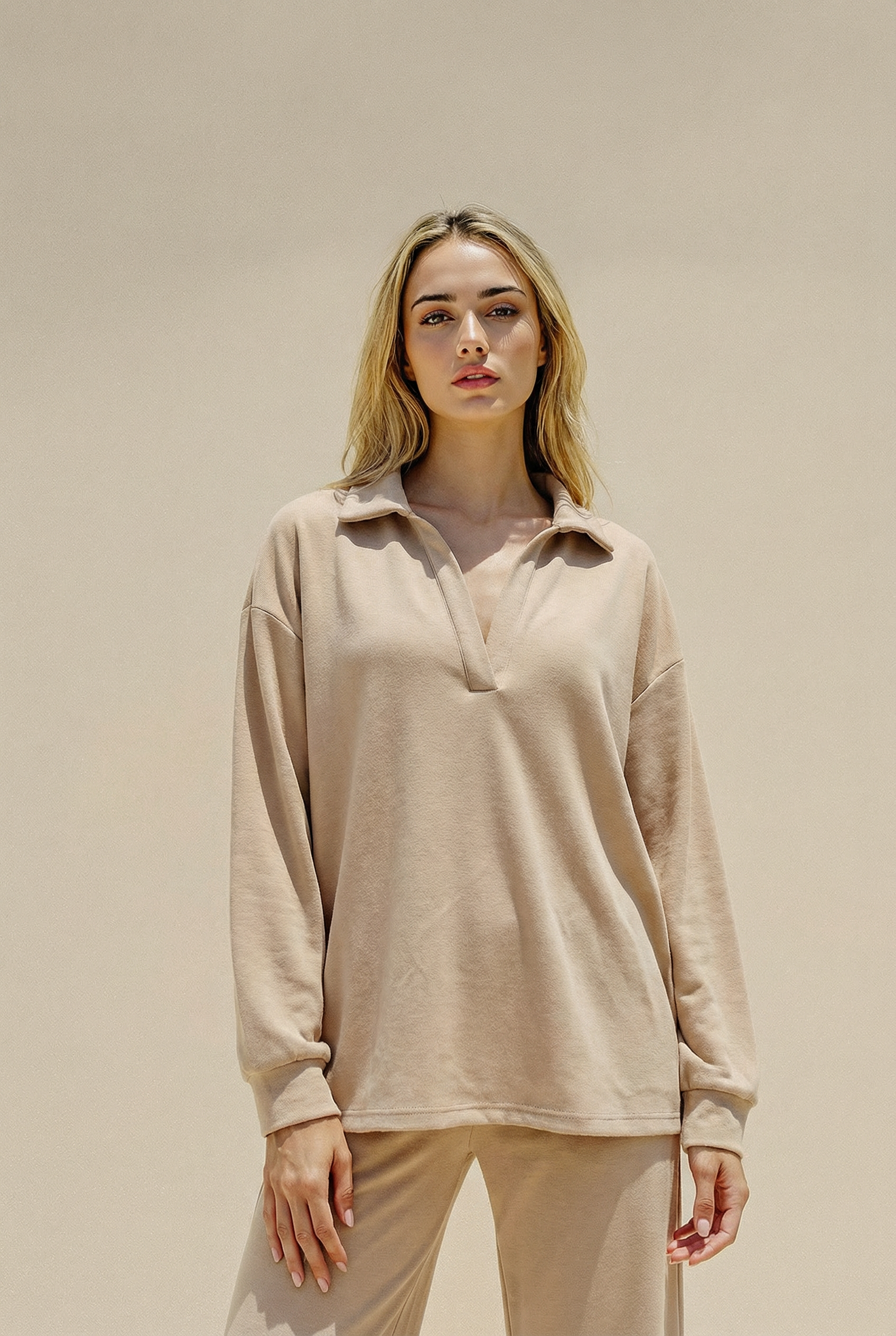 Woman wearing a beige long-sleeve top and pants against a beige background