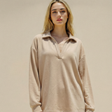 Woman wearing a beige long-sleeve top and pants against a beige background