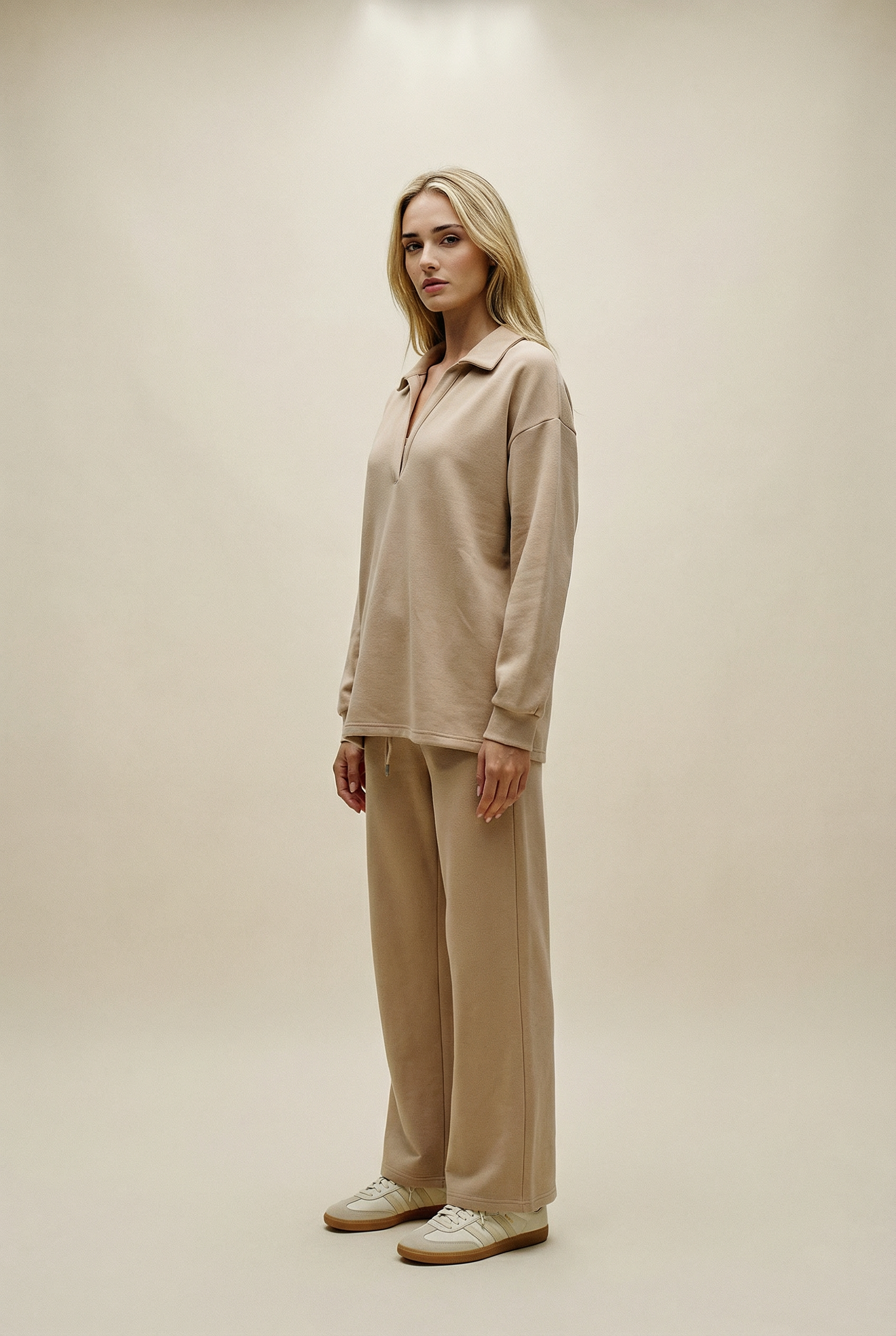 Woman wearing a beige outfit against a plain background