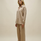 Woman wearing a beige outfit against a plain background