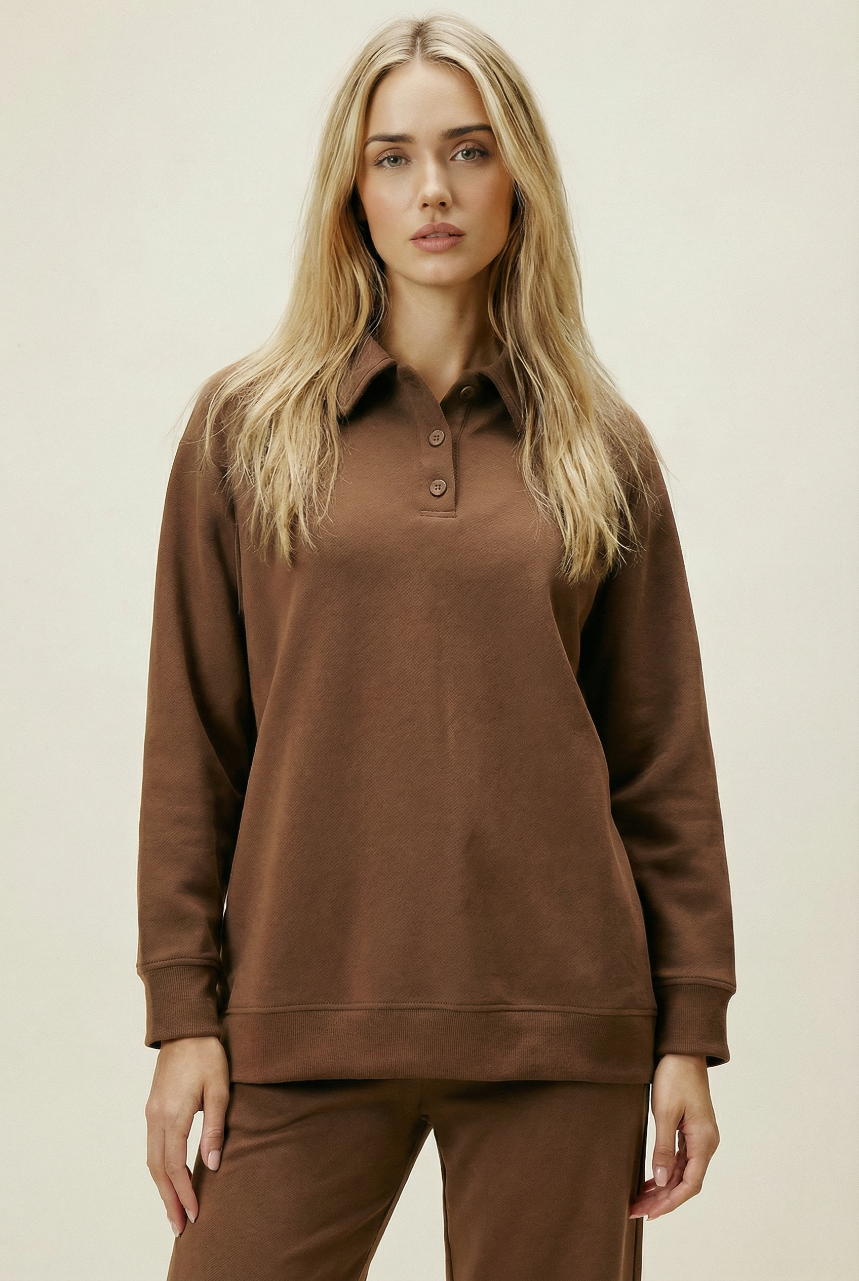 Woman wearing a brown long-sleeve shirt and pants on a beige background