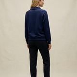 Person wearing a navy blue jacket and black pants on a beige background