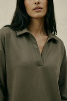 Woman wearing a green shirt against a neutral background