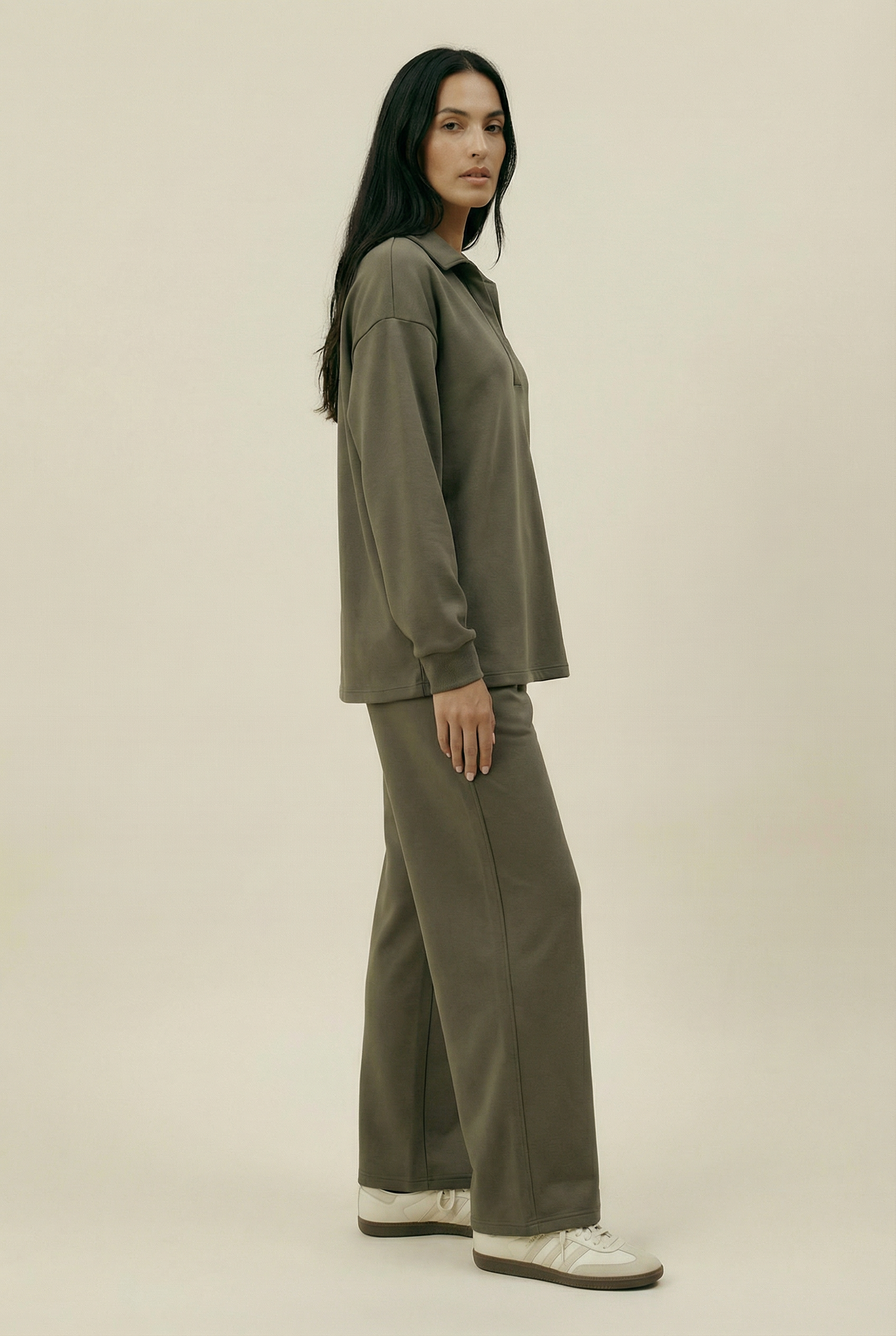 Woman wearing an olive green outfit on a beige background