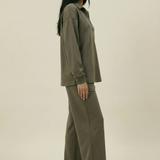 Woman wearing an olive green outfit on a beige background
