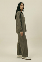 Woman wearing an olive green outfit on a beige background